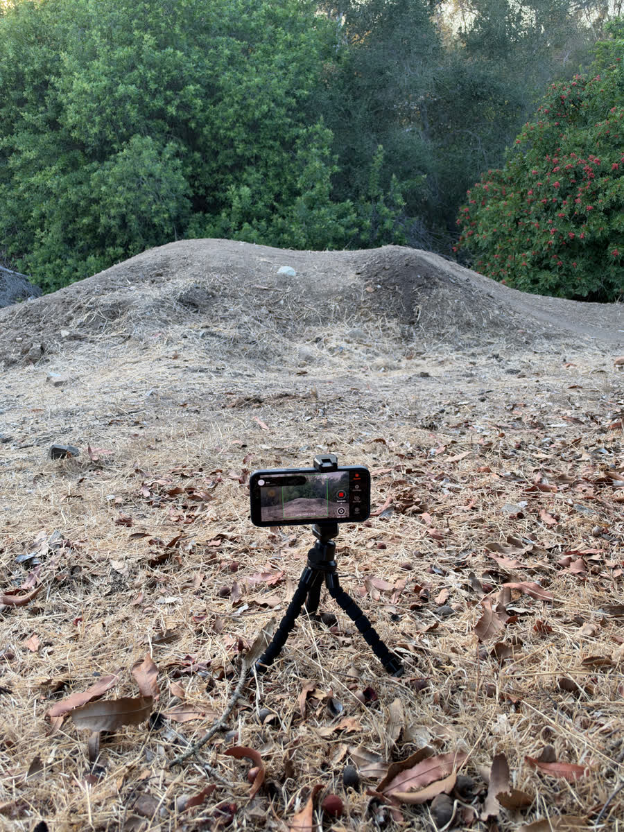 A phone on a small tripod facing a dirt jump